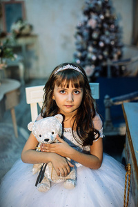 可爱的小女孩摆着圣诞装饰，穿着白色连衣裙和皇冠