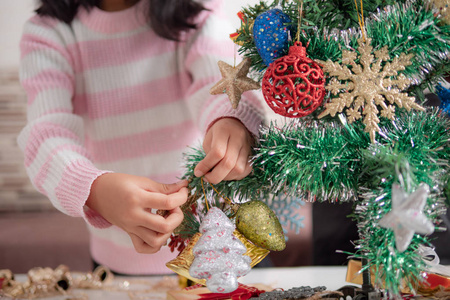 亚洲小女孩为欢乐派对装饰圣诞树选焦点浅野