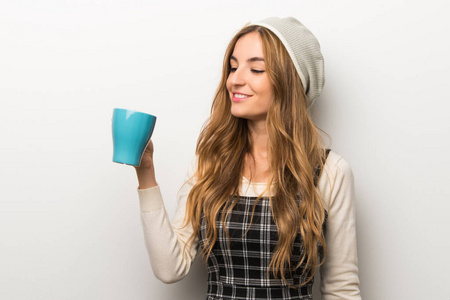时髦的女人戴着帽子拿着一杯热咖啡