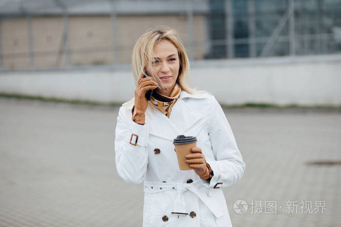 办公楼附近有咖啡杯的漂亮女人. 近距离观看一个大城市的年轻女