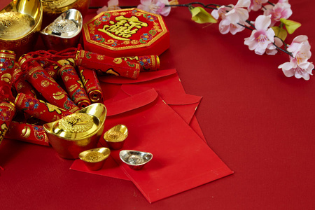 中国新年2019年节日装饰品。鞭炮金锭包花红色背景。 顶部视图附件。 翻译福意吉祥，春意春天。