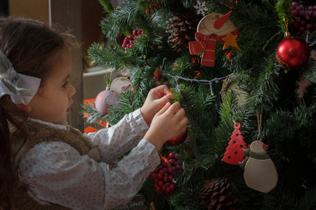 小女孩用红球和其他玩具装饰圣诞树