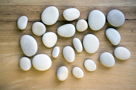 木制垫子上的一组禅宗石头，鹅卵石，浅灰色，深灰色，白色按摩卵石