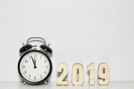 新年快乐概念与闹钟和木制号码2019在白色墙壁背景，复制空间。