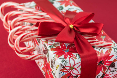 包装糖果盒在圣诞纸，装饰红色蝴蝶结和糖果罐在红色背景圣诞节礼物。贺卡的概念。