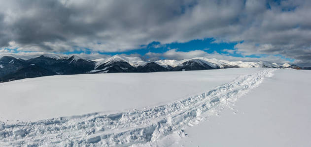 雪撬的痕迹和脚印在冬季的山顶和雪覆盖着风景如画的阿尔普山脊乌克兰喀尔巴阡山宁静，宁静，从德森布罗尼亚村郊区。