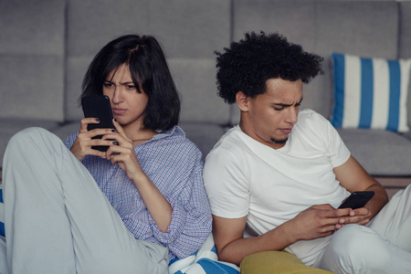 轻松的情侣或朋友使用泛型手机一起坐在家里的客厅里的沙发上
