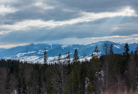 傍晚，冬天的雪覆盖了阿尔卑斯山的山脊，阳光从多云的天空乌克兰喀尔巴阡山脉。