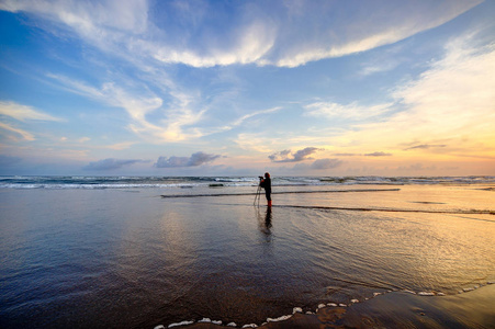 日落时，孤独的摄影师在瘦骨嶙峋的海滩上。 印尼爪哇中部。