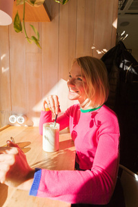 一位年轻女子坐在咖啡馆的桌旁, 享受着早晨的饮料