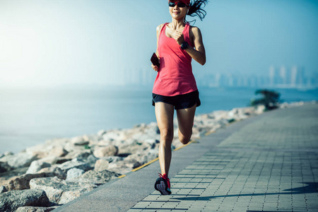 健身女运动员在阳光明媚的海岸跑步照片