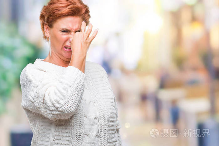 可爱的高级白种人红头发的女人穿着冬天的毛衣,在孤立的背景上闻着