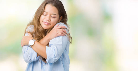 年轻美丽的黑发商务女性在孤立的背景下拥抱自己,快乐而积极的微笑