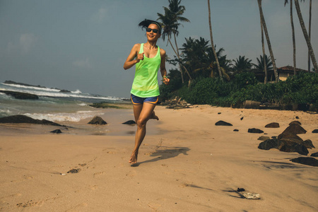 健康的生活方式观念年轻女性早晨日出时在热带海滩跑步