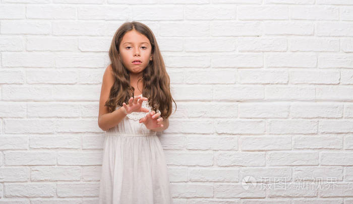 年轻的西班牙裔孩子在白色砖墙上厌恶的表情不高兴和恐惧做厌恶的脸