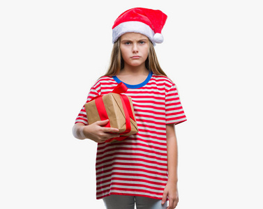 年轻漂亮的女孩戴着圣诞帽，在孤立的背景上拿着礼物，聪明的脸上带着自信的表情，严肃的思考着