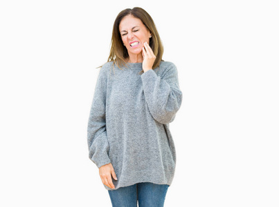 美丽的中年妇女穿着冬天的毛衣，在孤立的背景下，用手摸嘴，因为牙痛或牙齿上的牙齿疾病，表情痛苦。牙医的概念。