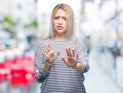 年轻的金发女人在孤立的背景下厌恶的表情，不高兴和恐惧做厌恶的脸，因为厌恶的反应。举起双手。令人讨厌的概念。