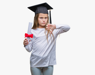 年轻漂亮的女孩戴着研究生帽，带着学位，带着愤怒的脸，带着消极的信号，用拇指向下表示不喜欢，拒绝的概念