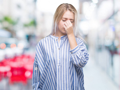 年轻的金发女人在孤立的背景下疲惫地鼻子和眼睛，感到疲劳和头痛。压力和挫折的概念..