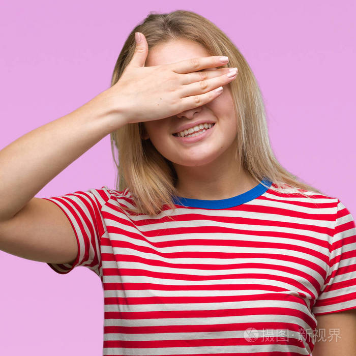 年轻的白种人女人在孤立的背景上微笑和笑,用手捂着眼睛,以求惊喜.
