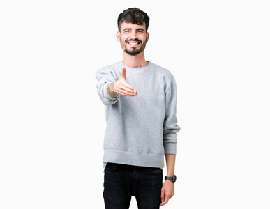 年轻的帅哥穿着运动衫，在孤立的背景上微笑，友好地提供握手作为问候和欢迎。 成功的生意。