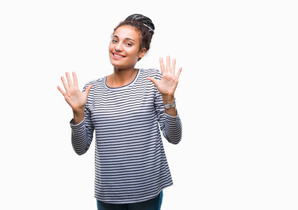 年轻的辫子，非洲裔美国女孩穿着毛衣，在孤立的背景上，显示和指着10号手指，同时微笑自信和快乐。