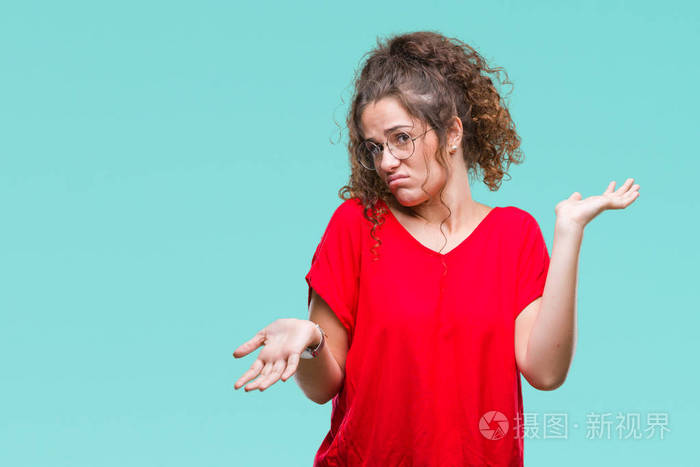 美丽的黑发卷发年轻女孩戴着眼镜,在孤立的背景上毫无头绪,表情混乱,
