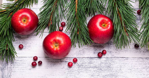 圣诞背景与树枝，红苹果和蔓越莓。 轻木桌。 上面的风景。 复制空间