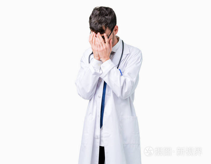 年轻的医生穿着医院外套在孤立的背景上悲伤的表情覆盖着脸双手哭泣