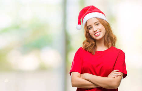年轻漂亮的女人在孤立的背景上戴着圣诞帽，快乐的脸，交叉着手臂看着相机。 积极的人。