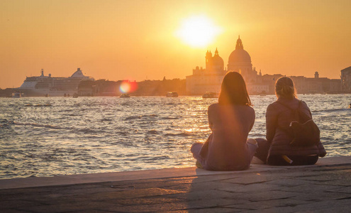 两个女孩欣赏圣玛丽亚德拉在威尼斯敬礼的风景日落。