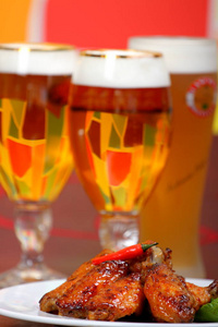 在白色的盘子上，锋利的鸡翅，在彩色的背景上啤酒