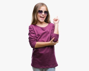 年轻漂亮的女孩戴着太阳镜在孤立的背景上，脸上带着大大的微笑，用手和手指指向一边，看着相机。