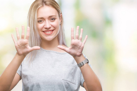 年轻的金发女人在孤立的背景上显示和指着数字10，同时微笑自信和快乐。