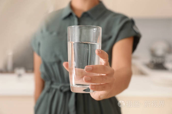 女人在厨房的特写镜头里拿着玻璃和纯净水