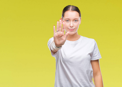 年轻美丽的白种人女人在孤立的背景下做停止用手掌唱歌。 警告表情，脸上有负面和严肃的手势。