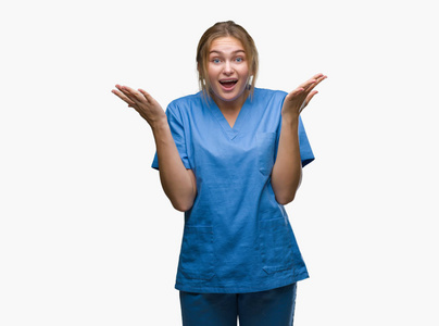 年轻的白种人护士穿着外科医生制服，在孤立的背景下庆祝疯狂和惊讶的成功，举起手臂和睁开眼睛尖叫兴奋。赢家概念