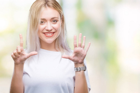 年轻的金发女子在孤立的背景显示和指向7号手指，同时微笑自信和快乐。