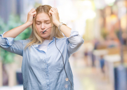 年轻的白种人商务女性戴着呼叫中心耳机，在孤立的背景下患有头痛，绝望和压力，因为疼痛和偏头痛。手放在头上。
