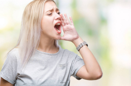 年轻的金发女人在孤立的背景上大声喊叫，并大声尖叫，手在嘴上。传播概念。