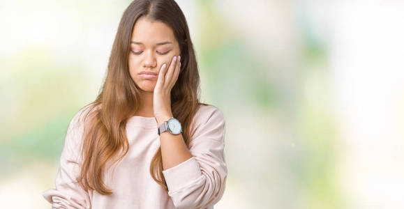 年轻漂亮的黑发女人穿着粉红色的运动衫，在孤立的背景下思考，看起来疲惫，厌倦了交叉双臂的抑郁问题。