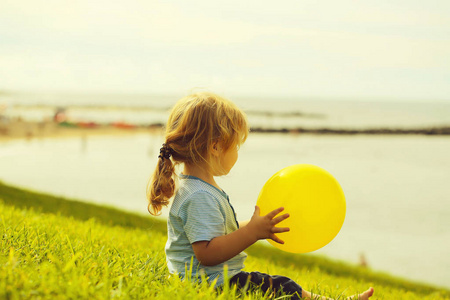 可爱的小宝贝男孩与黄色玩具气球
