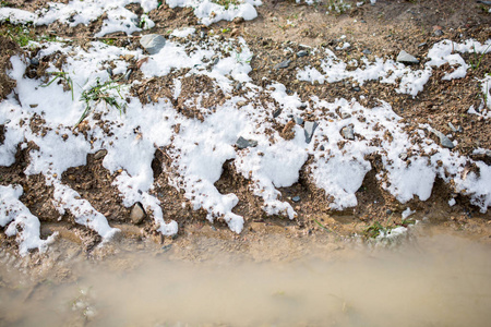 冬天在岩石和泥泞的表面上的白雪