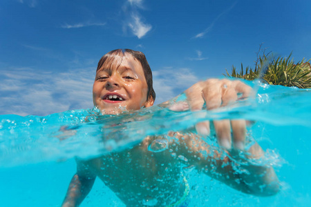 接近快乐的青春期前男孩在户外游泳池游泳和看相机的肖像。