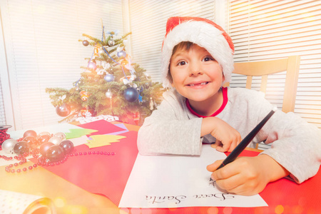 s hat sitting at the table, writing a Christmas letter and looki