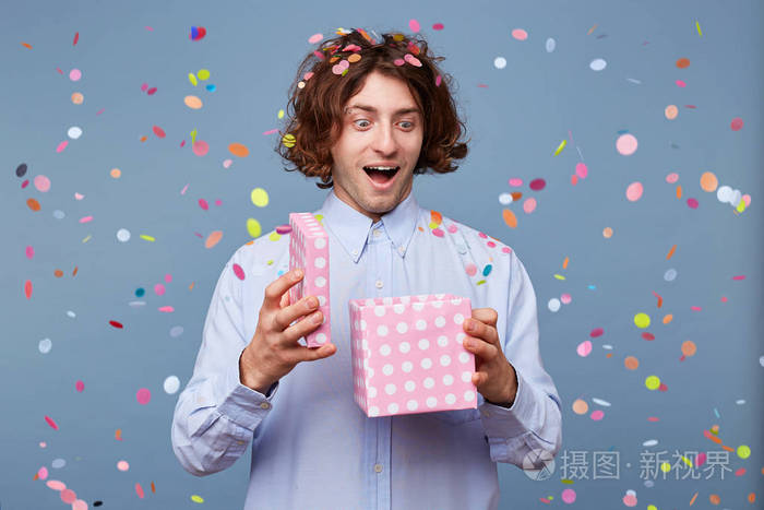 快乐的节日活泼的生日家伙拿着礼物的盒子打开它看着高兴的高兴收到一