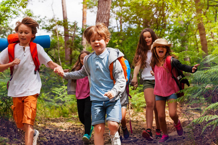 孩子们在森林里奔跑的肖像，在学校的自然露营旅行中，他们手拉手在小径上奔跑