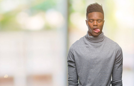 年轻的非裔美国男人在孤立的背景下伸出舌头，用有趣的表情高兴。 情感概念。