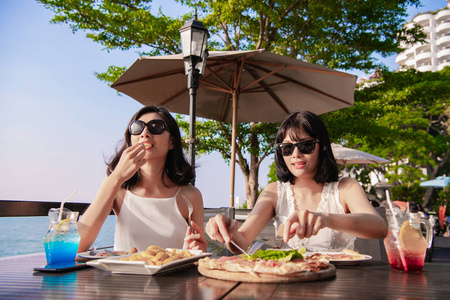 休闲概念。 美丽的女孩正在海边餐馆吃饭。 美丽的女孩正在享受桌子上的食物。